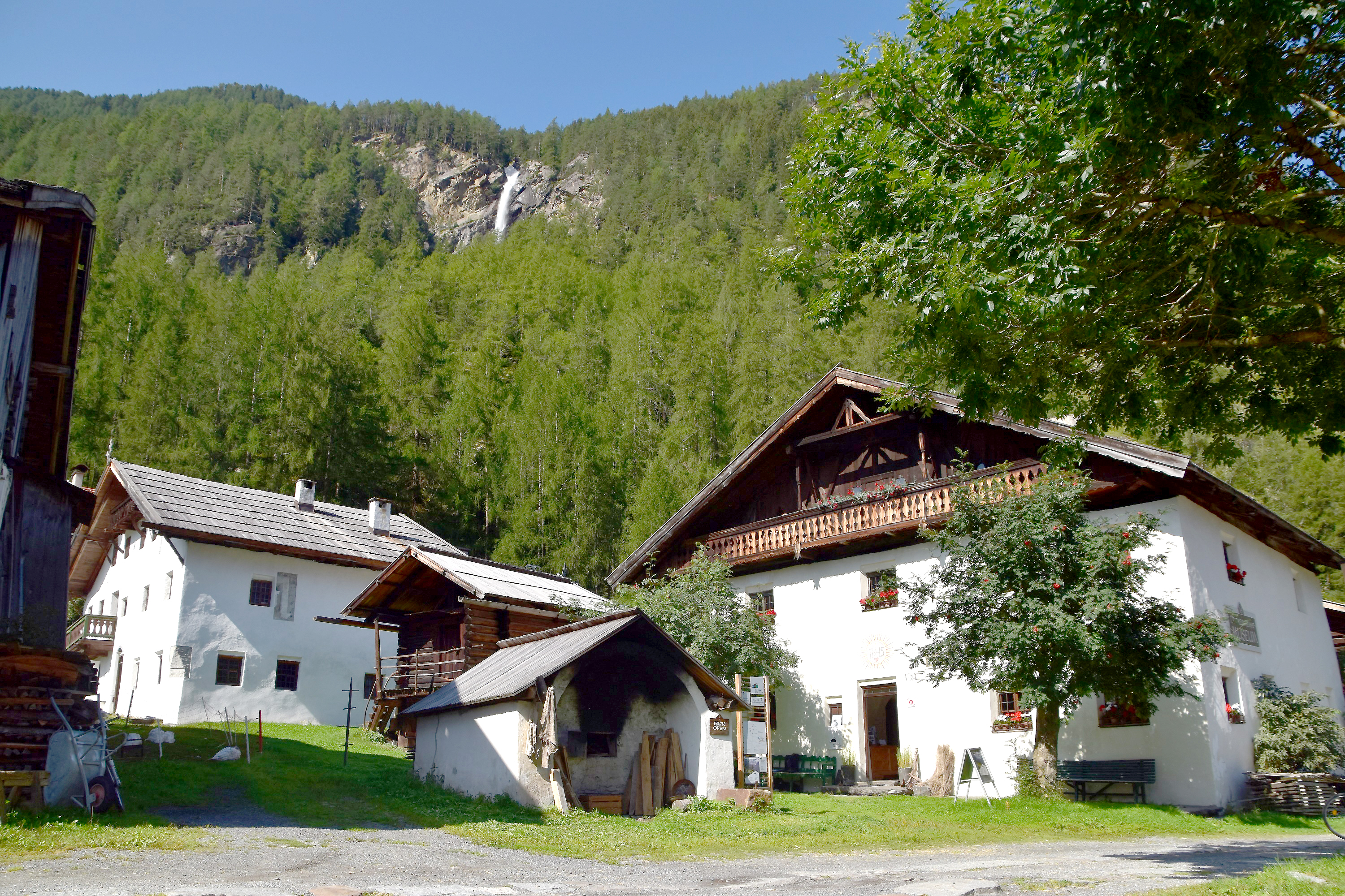 Gebäude des Ötztaler Heimatmuseums vor bewaldetem Gebirgsausläufer im Hintergrund.