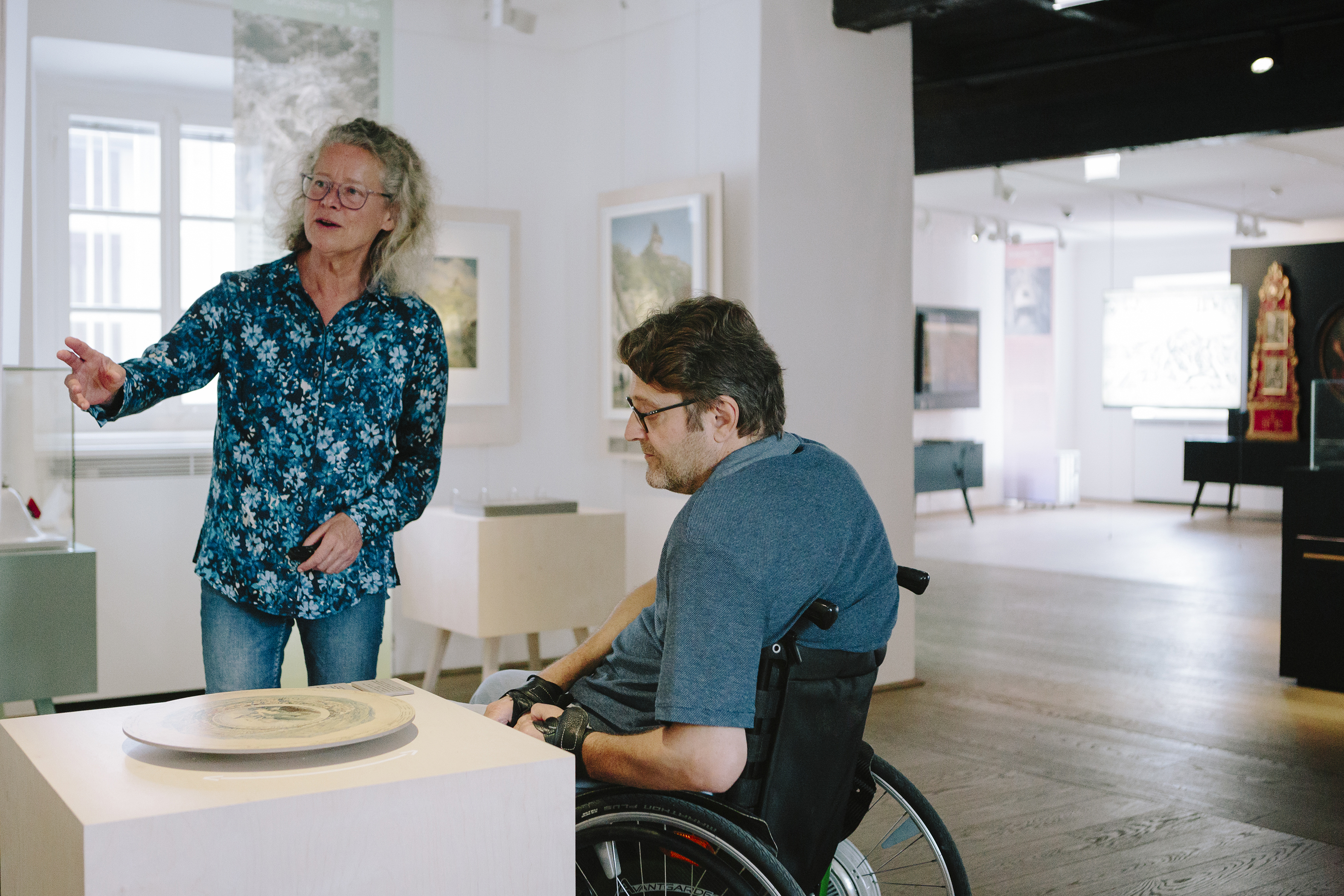Foto einer Führung im Graz MuseumSchlossberg. Ein Mann im Rollstuhl betrachtet ein Keramikobjekt.