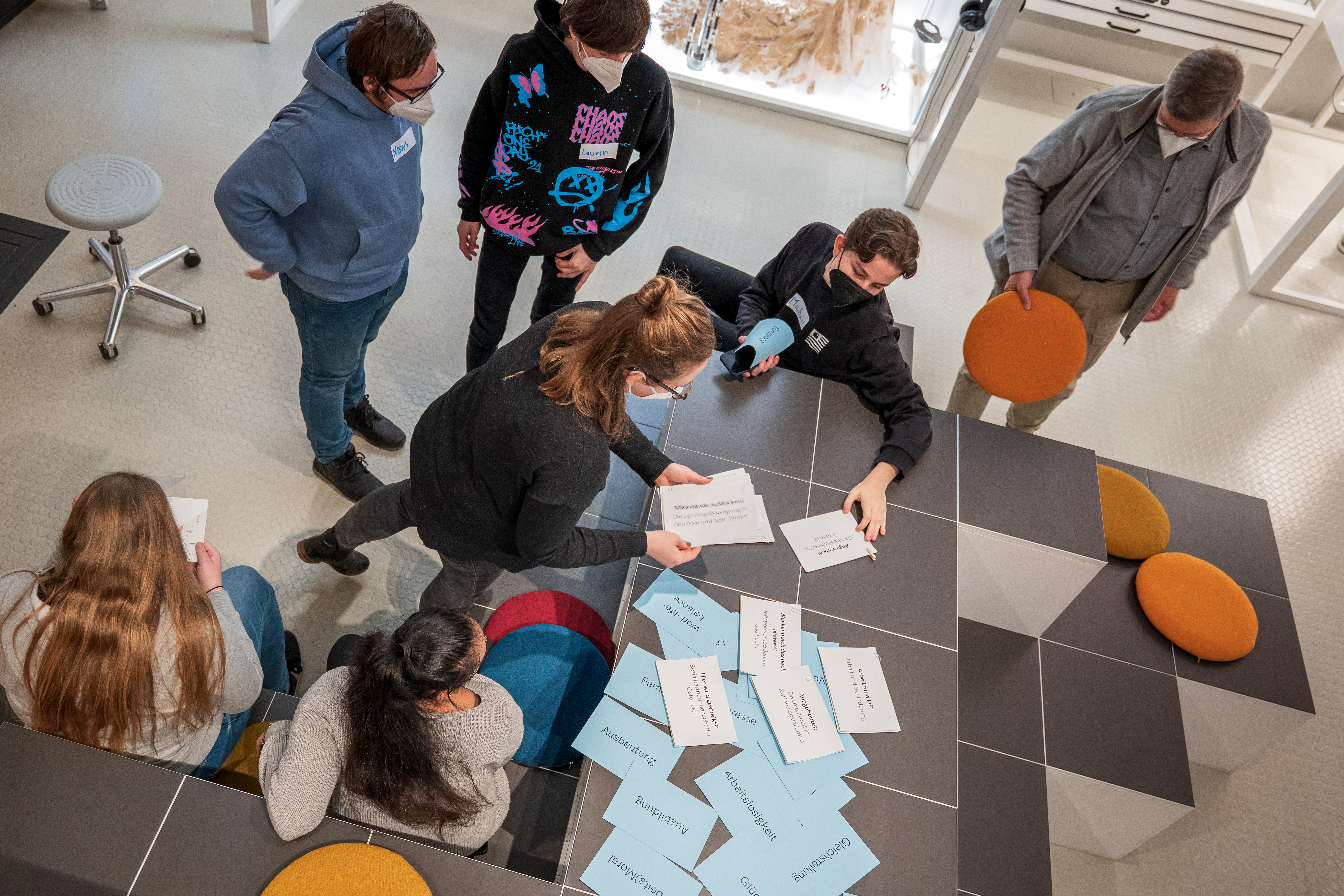 Foto einer Gruppe von Museumsbesuchern, die sich in einem Workshop mit dem Ausstellungsmaterial beschäftigen.