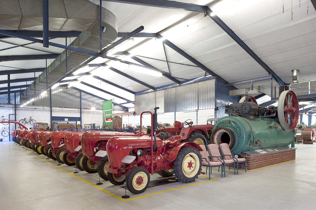 Foto einer Ausstellungshalle im Landtechnikmuseum Burgenland mit diversen historischen in der Landwirtschaft eingesetzten Maschinen. Besonders sticht die lange Reihe an roten Traktoren hervor.