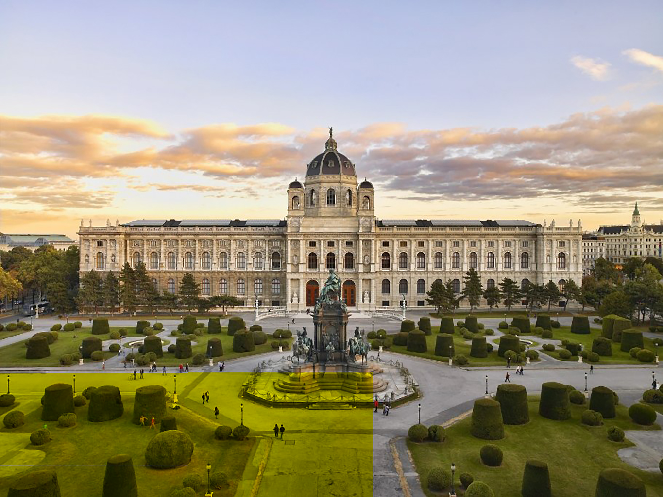 Luftaufnahme des Kunsthistorischen Museums Wien inklusive dem gesamten begrünten Vorplatz bei Abenddämmerung.