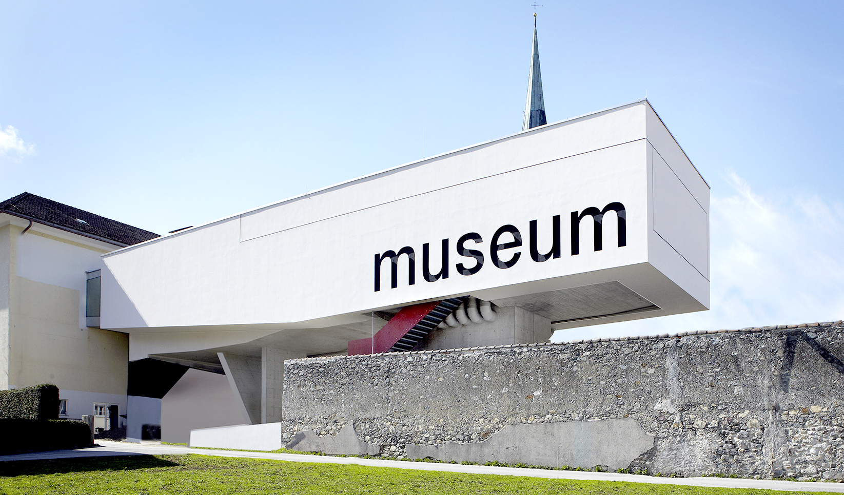 Foto des horizontal aus dem Hauptgebäude herausragenden, auf Säulen stehenden und in großen Buchstaben mit "museum" beschrifteten Gebäudeteils des Museums der Völker.