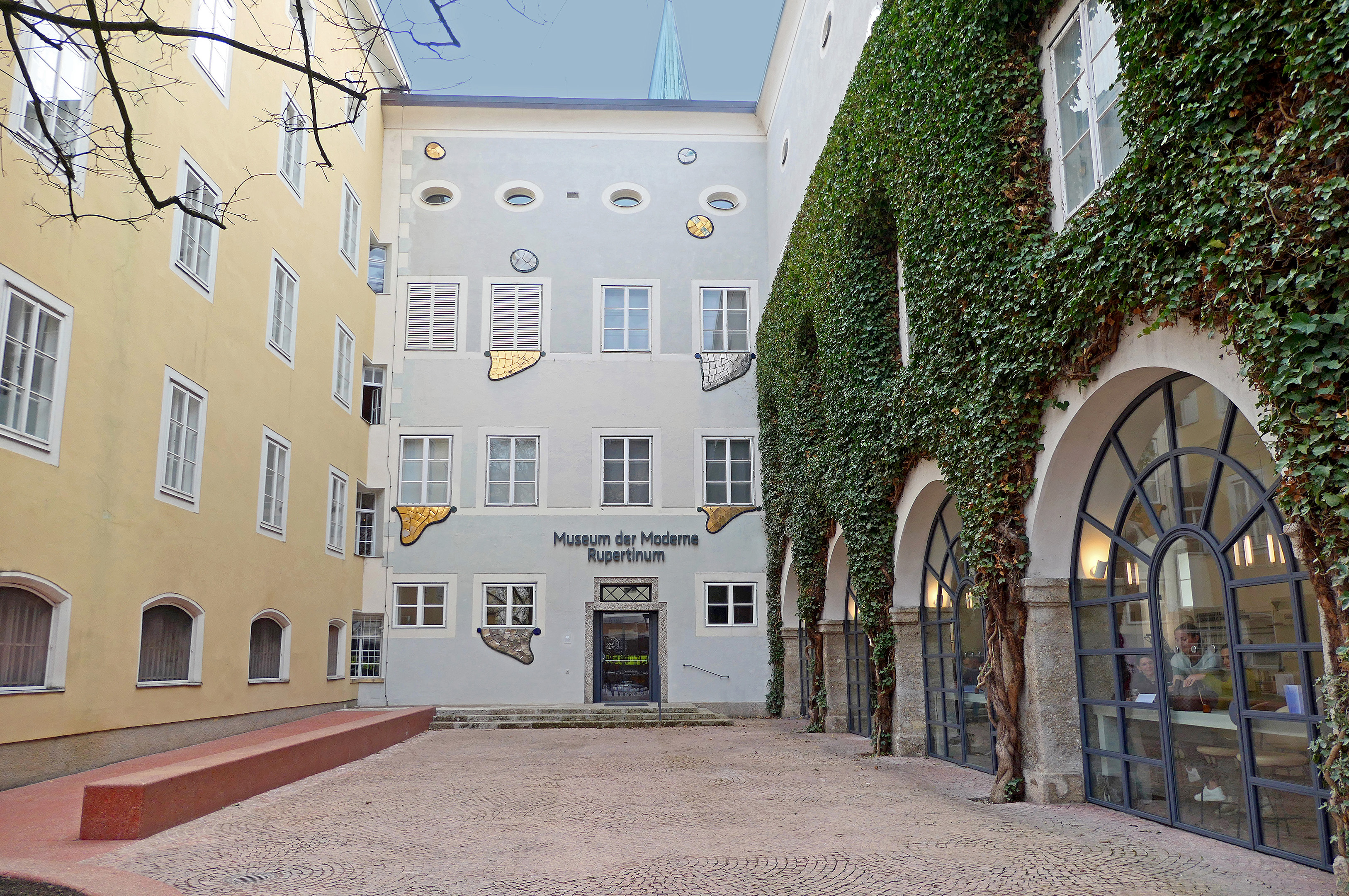 Innenhof vor dem Rupertinum. Das den Innenhof rechts begrenzende Gebäude ist bis zum zweiten Stock vollständig mit Efeu bedeckt.