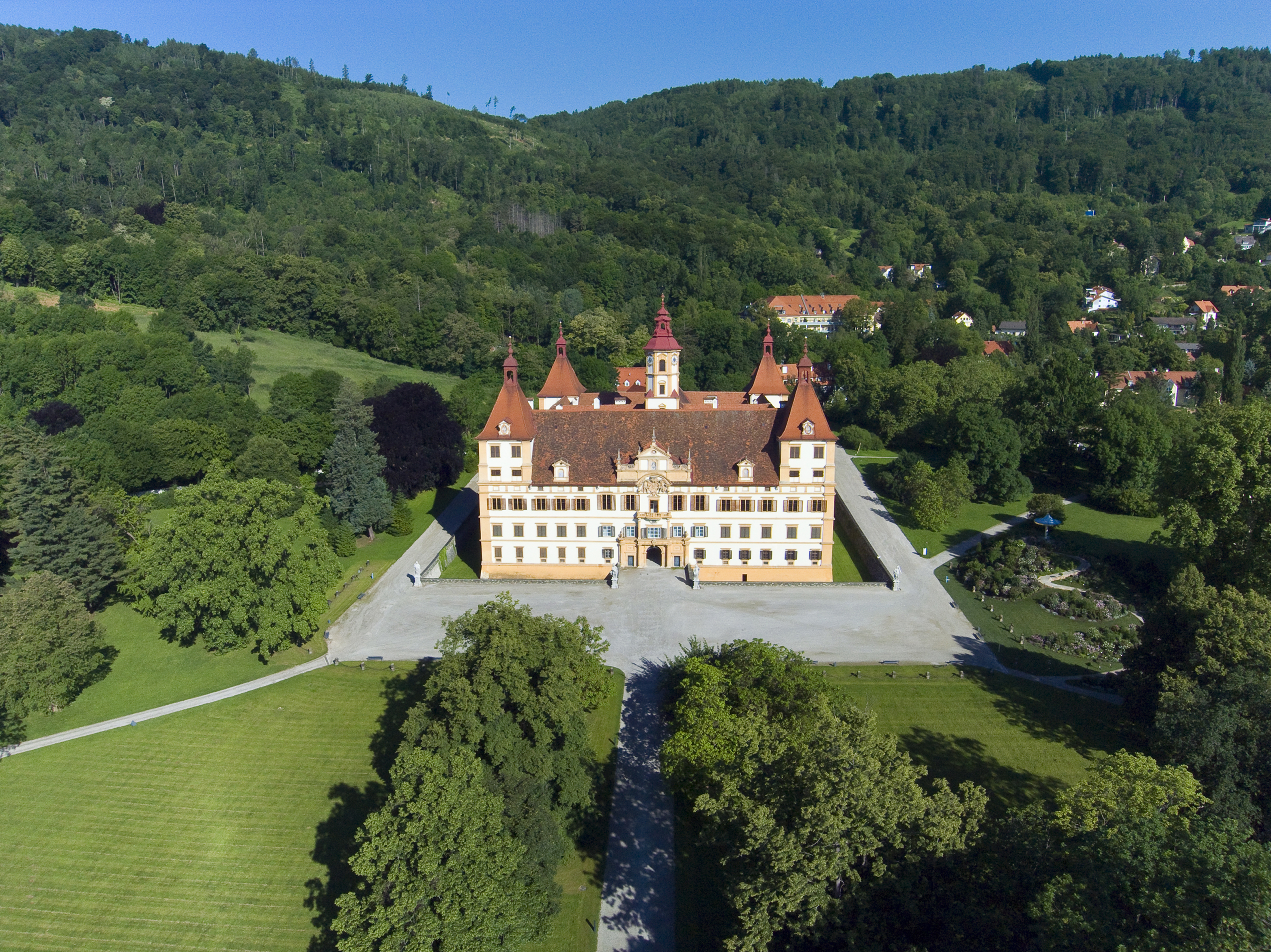 Luftaufnahme des Schloss Eggenbergs und der umliegenden Waldlandschaft.