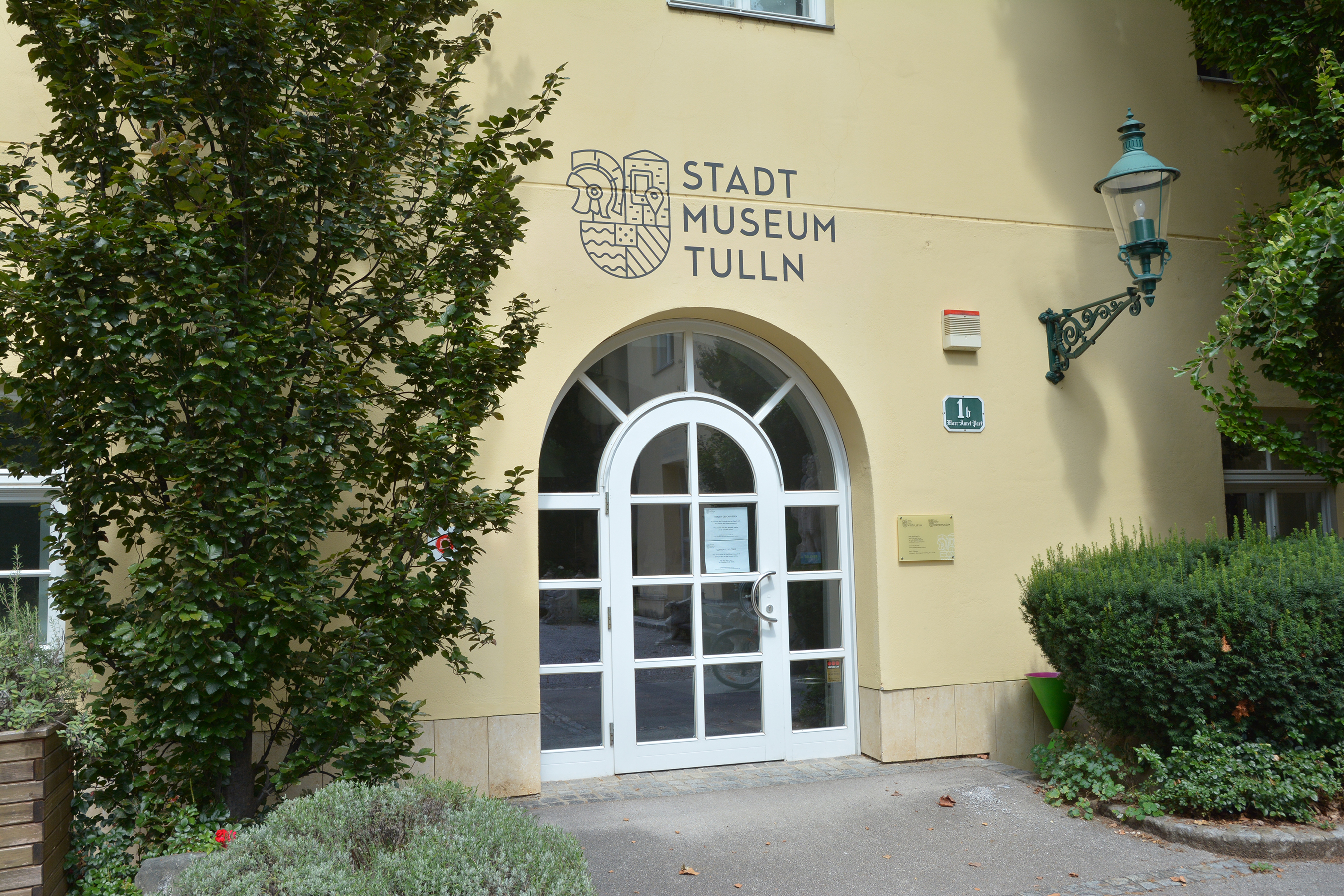 Foto des Eingangs zum Stadtmuseum Tulln. Über dem Eingang ist neben dem Schriftzug "Stadtmuseum Tulln" das wappenartige Logo des Museums zu sehen.