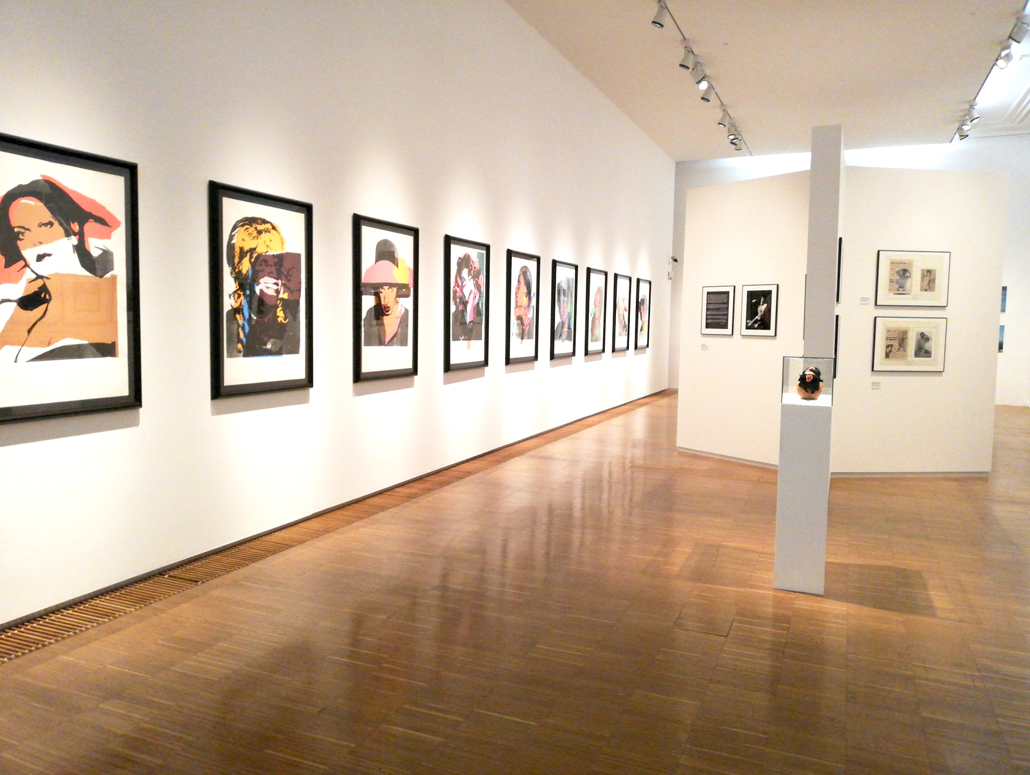 Foto eines Ausstellungraums in der Neuen Galerie Graz mit vielen zeitgenössischen Porträts an der Wand hängend.