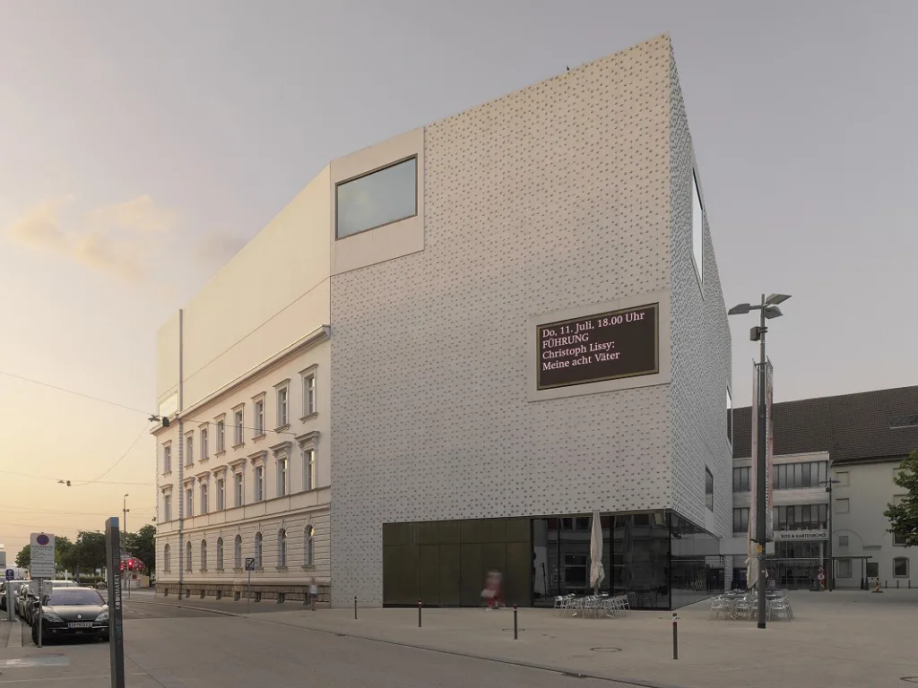 Foto des Vorarlberg Museums von der gegenüberliegenden Straßenseiten bei Abenddämmerung.