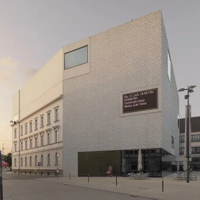 Foto des Vorarlberg Museums von der gegenüberliegenden Straßenseiten bei Abenddämmerung.