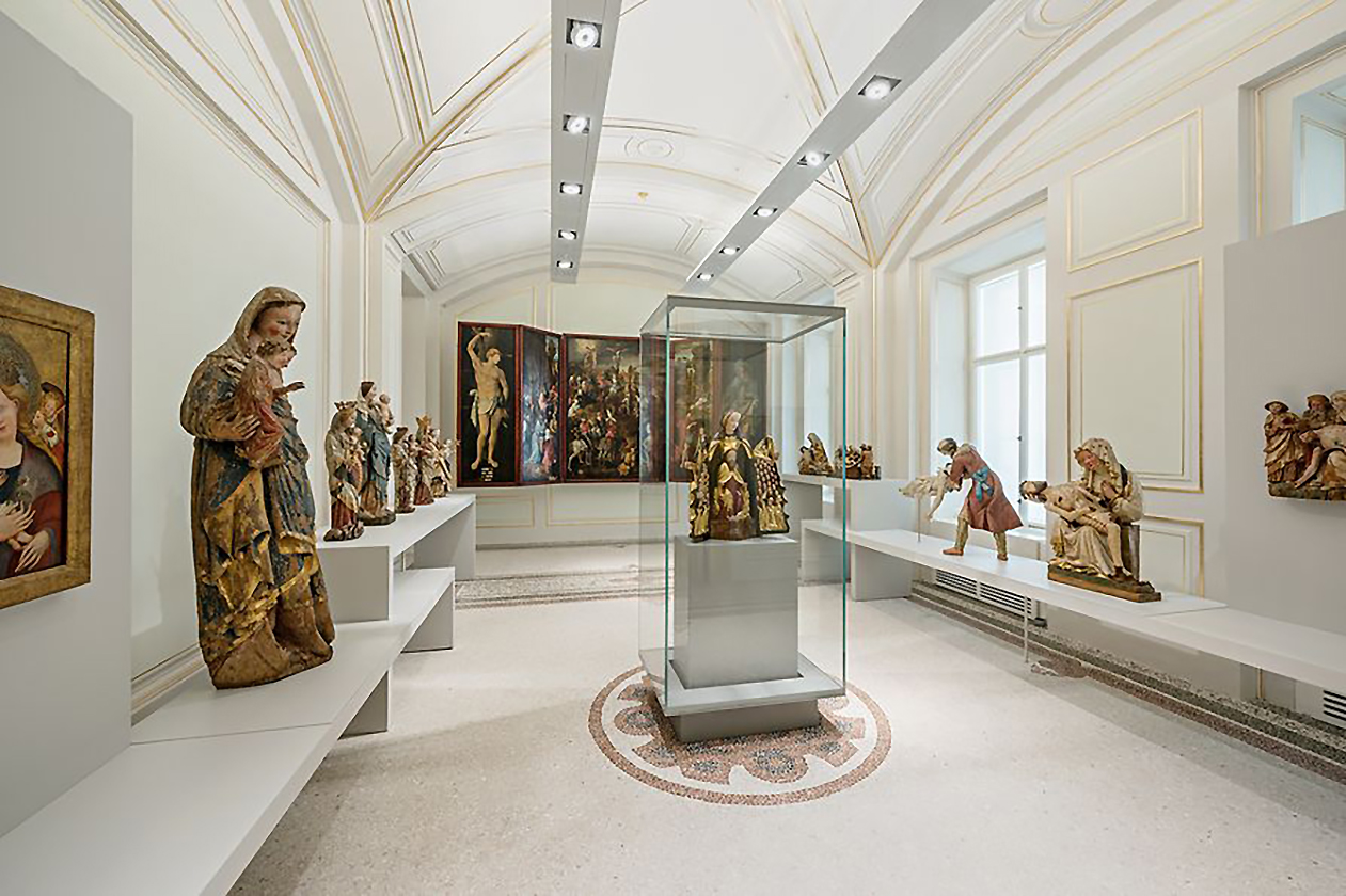 Foto eines Ausstellungsraums im Dom Museum Wien. Zu sehen sind mehrere religiöse Statuen und Gemälde.