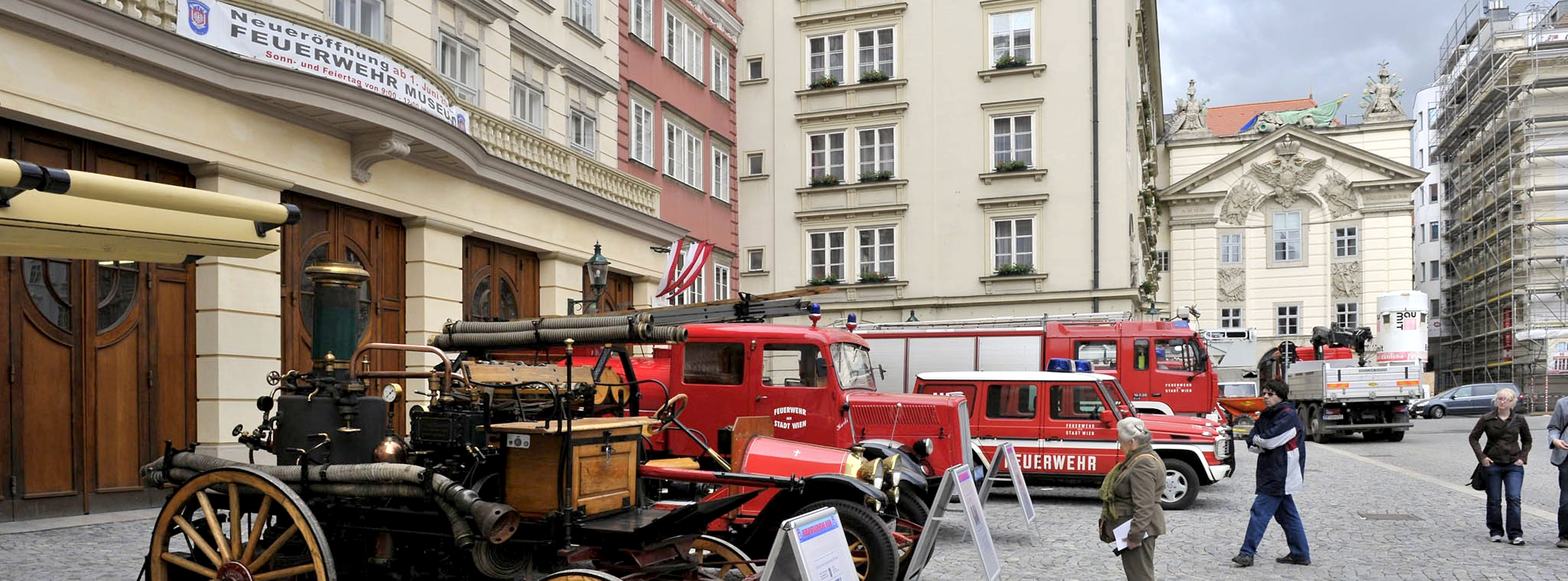 Foto von einer Reihe an historischen Feuerwehrfahrzeugen vor dem Feuerwehrmuseum Wien.