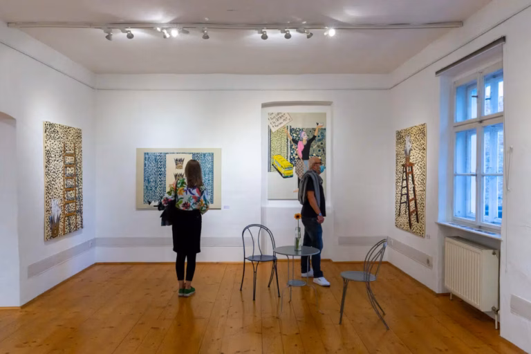 Besucher betrachten Gemälde und Zeichnungen in einer hellen Kunstgalerie