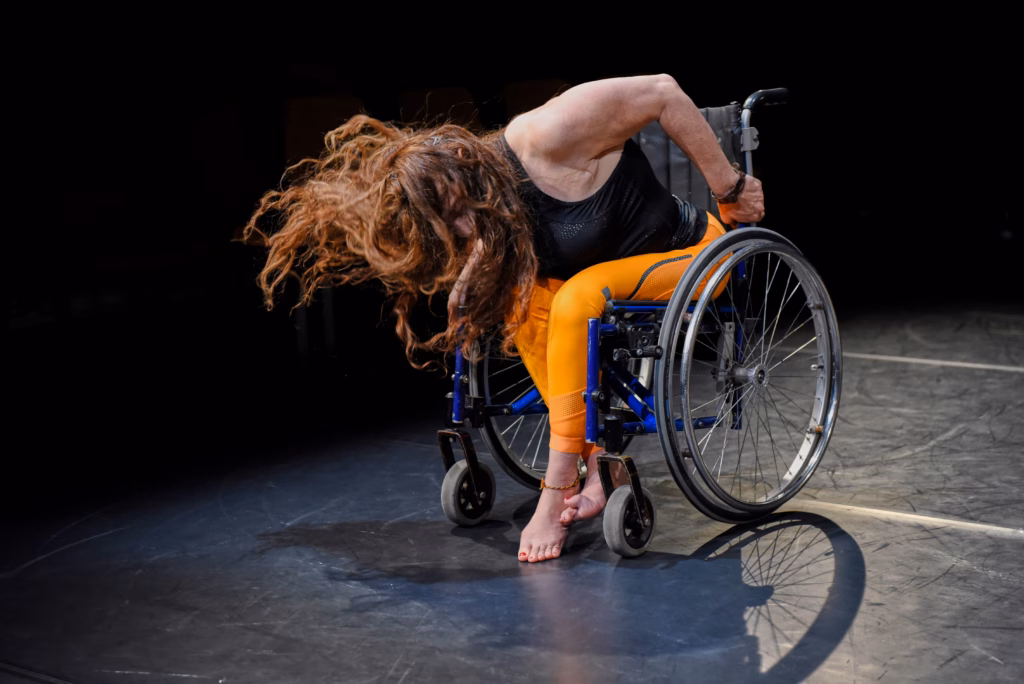 Tänzerin im Rollstuhl mit fliegendem Haar während einer expressiven Bewegung