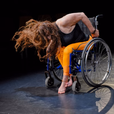 Tänzerin im Rollstuhl mit fliegendem Haar während einer expressiven Bewegung